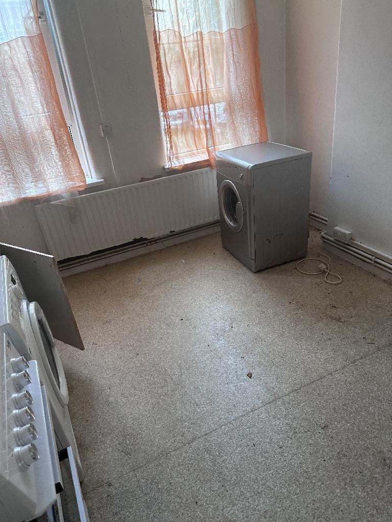 Flat clearance in Rotherhithe after completion, showing open space around the washing machine with the floor clutter removed