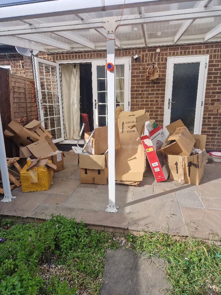 Household waste clearance in Romford before photo showing cardboard and packaging clutter on a patio area next to a brick home