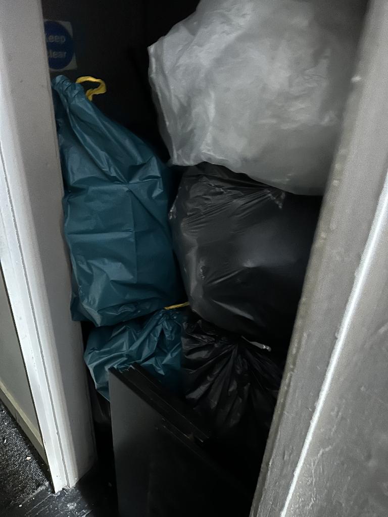 Internal household clearance in Clapham before service, showing waste bags blocking a narrow internal passage