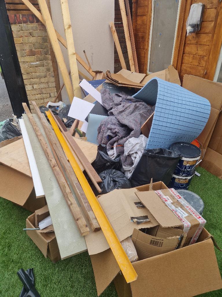 Rubbish removal before in Thames View: mixed renovation waste and building debris piled along the lawn border