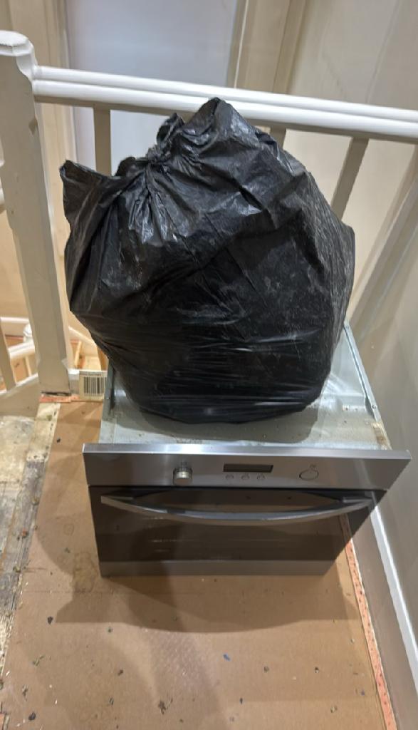 Rubbish removal in North Acton - before the clearance shows carpet rolls stacked and strapped in a room