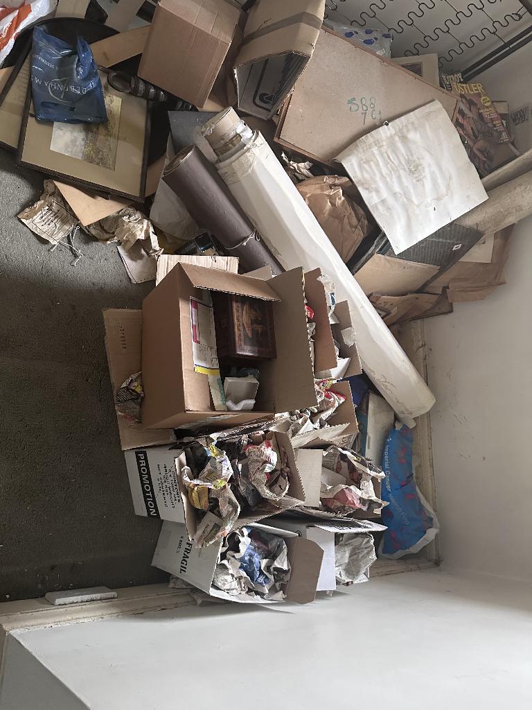 Flat clearance in Chelsea before service, showing stacked boxes and mixed waste