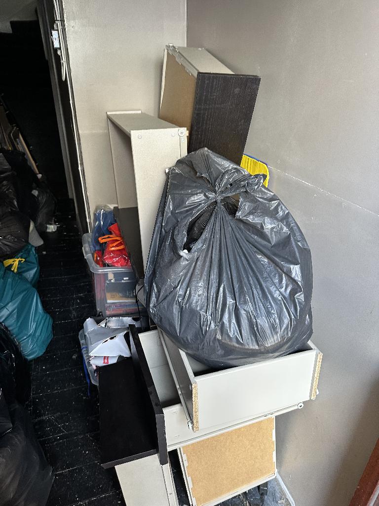 Internal household clearance in Clapham before service, showing bagged mixed waste piled on shelves and boxes