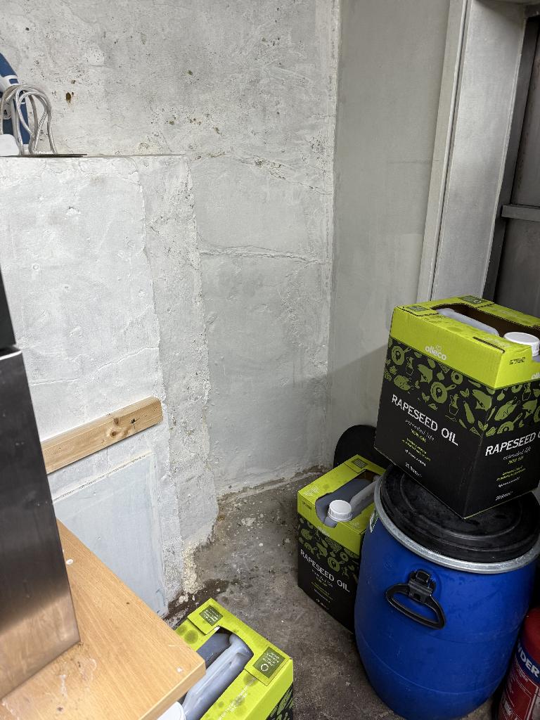 Household utility area clearance in Richmond after clearance showing cleared wall corner with grouped storage boxes and open floor