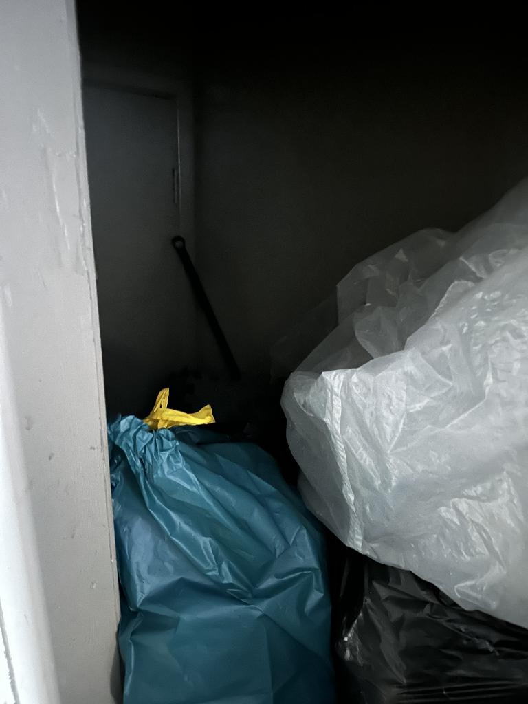 Internal household clearance in Clapham before service, showing tightly stacked waste bags in a confined storage corner