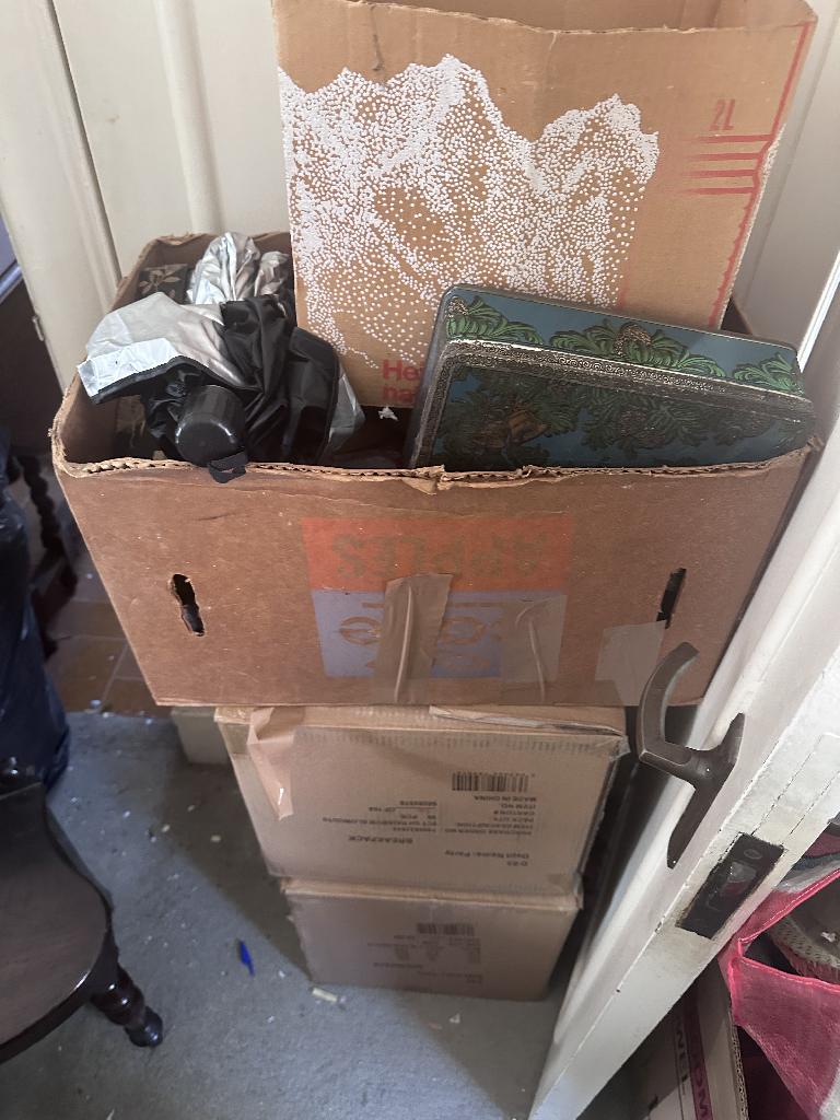 Household clutter clearance in Chelsea before service, showing stacked cardboard and waste bags