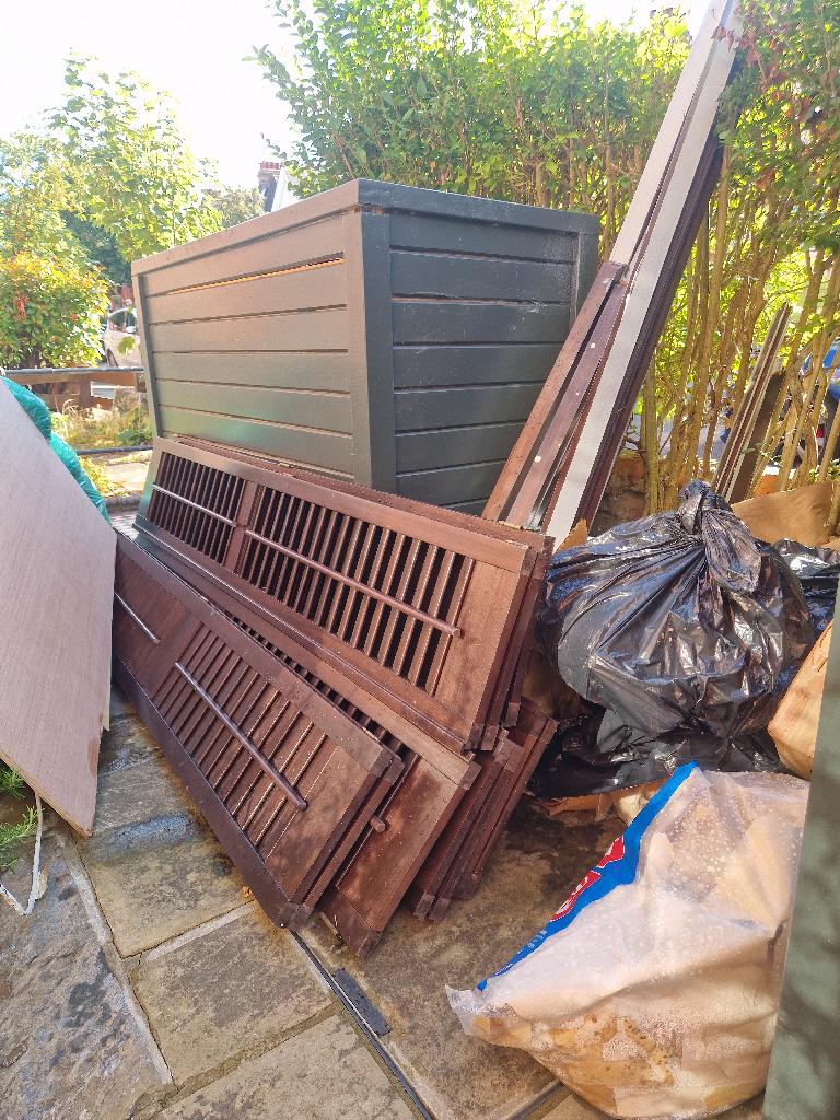 Garden and household waste clearance in Muswell Hill: before photo showing waste piled in the garden along the fence line