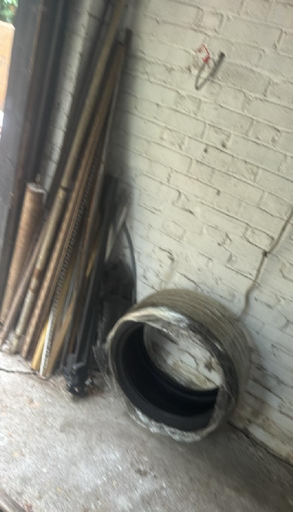 Rubbish removal in Walham Green before the clearance shows a narrow passage with stacked items and a large coil on the floor