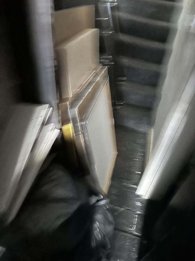 Internal household clearance in Clapham before service, showing bulky panels and cardboard waste stacked in a confined room