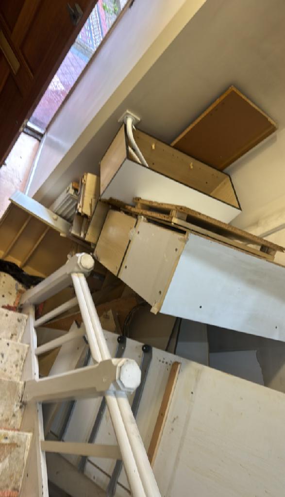 Furniture and bulky item removal in North Acton - before the clearance shows dismounted cabinet parts stacked in a stairwell area
