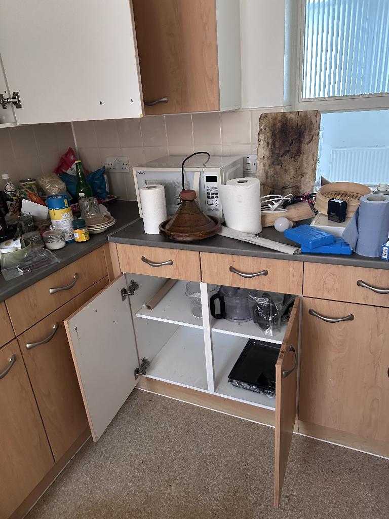 Flat clearance in Rotherhithe before the job, showing kitchen clutter and stacked kitchen items