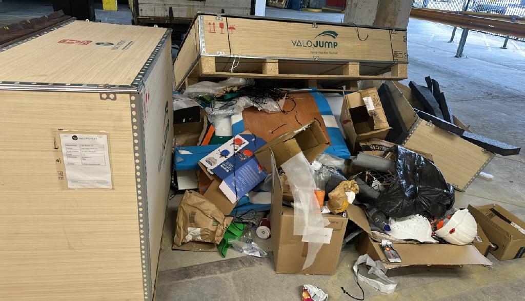 Household storage area clearance in Ilford before clearance, showing cardboard packaging and mixed waste piled inside a storage area