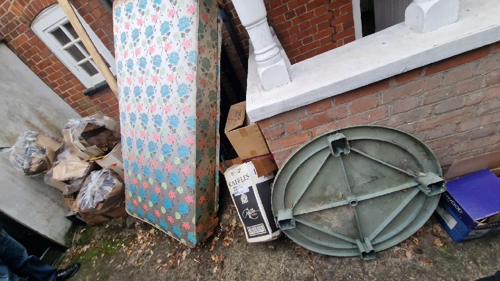 Front garden before clearance in Pinner South, close view of garden waste and boxes near the wall