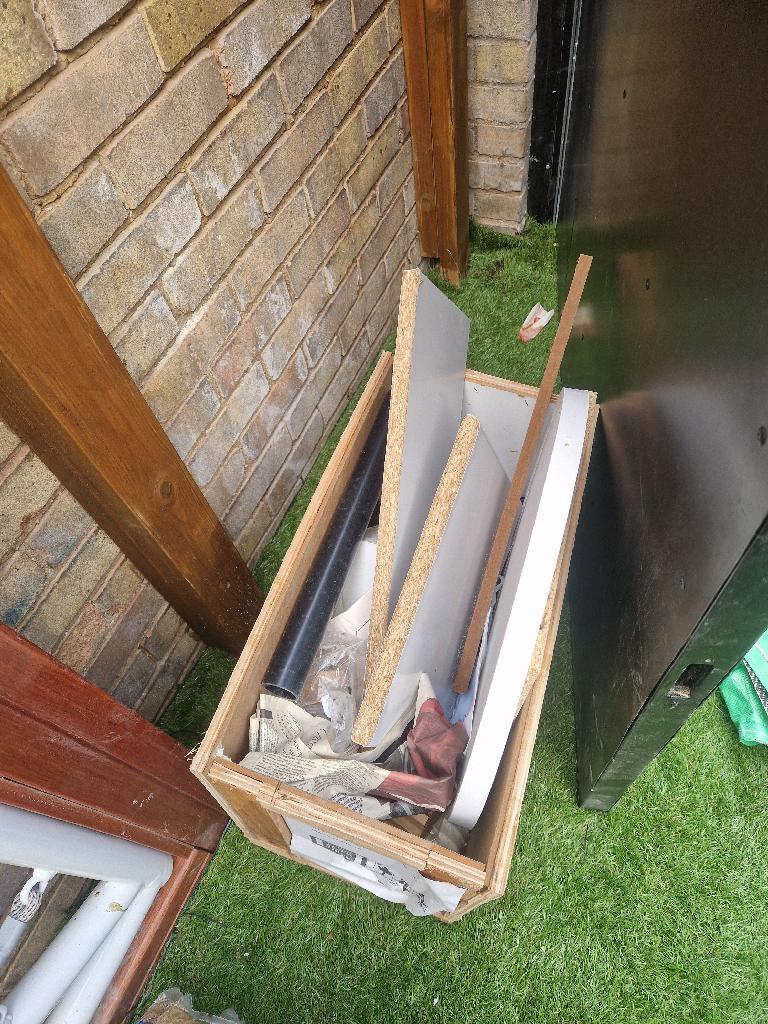 Rubbish removal before in Thames View: piles of building debris and boards positioned on the lawn near the doorway
