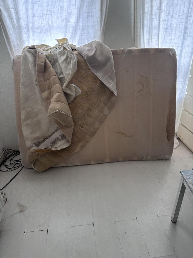 Flat clearance in Rotherhithe before the job, showing a room floor cluttered with bags and household items