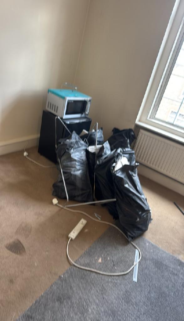 Home renovation waste clearance in Marylebone before clearance shows piled bin bags and debris in a room corner by the window