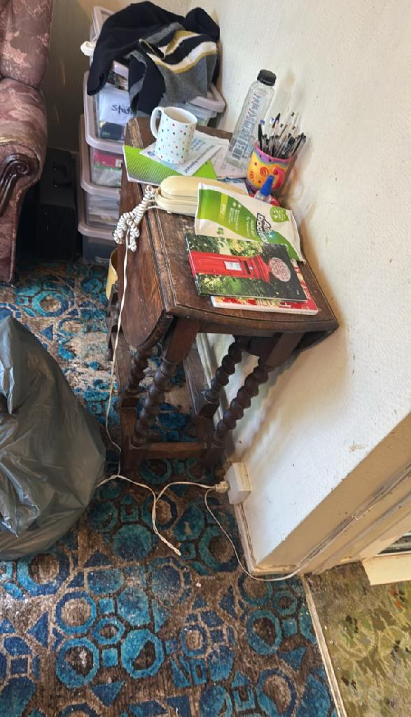 Side table clutter and bags on carpet in Wembley Park before rubbish removal