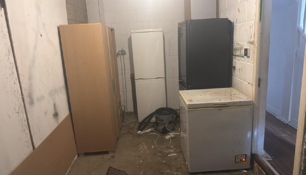 Household appliance and fridge clearance in Balham before service, showing appliances and debris clustered in a compact utility corner with cables across the floor