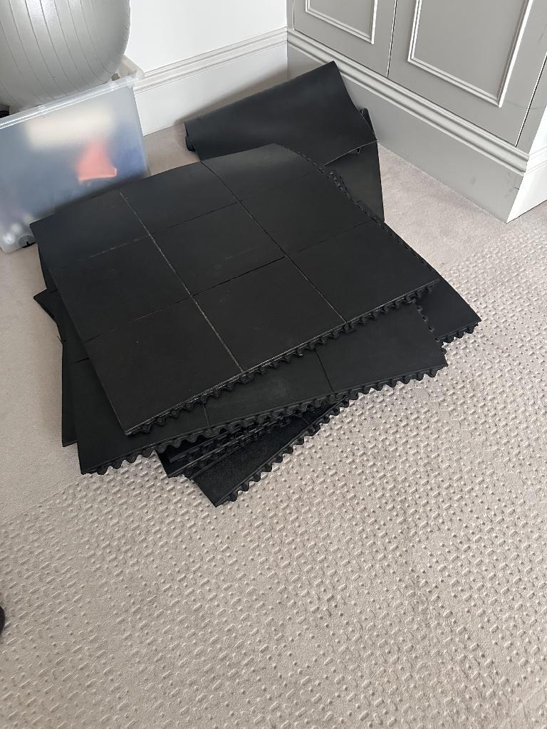 Home gym room clearance in Battersea before service, showing black exercise mat sections laid across the carpet in an indoor room